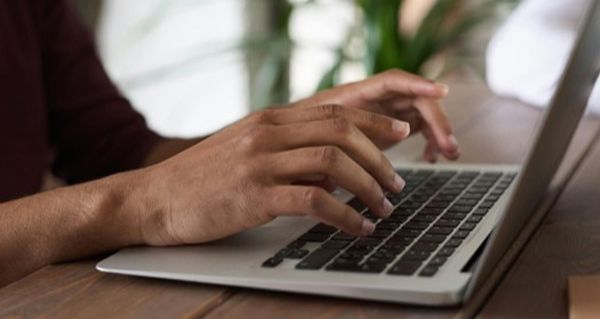 A close up of hands typing at a laptop.