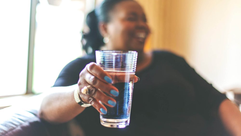 Adult African American woman smiling and holding a glass of water