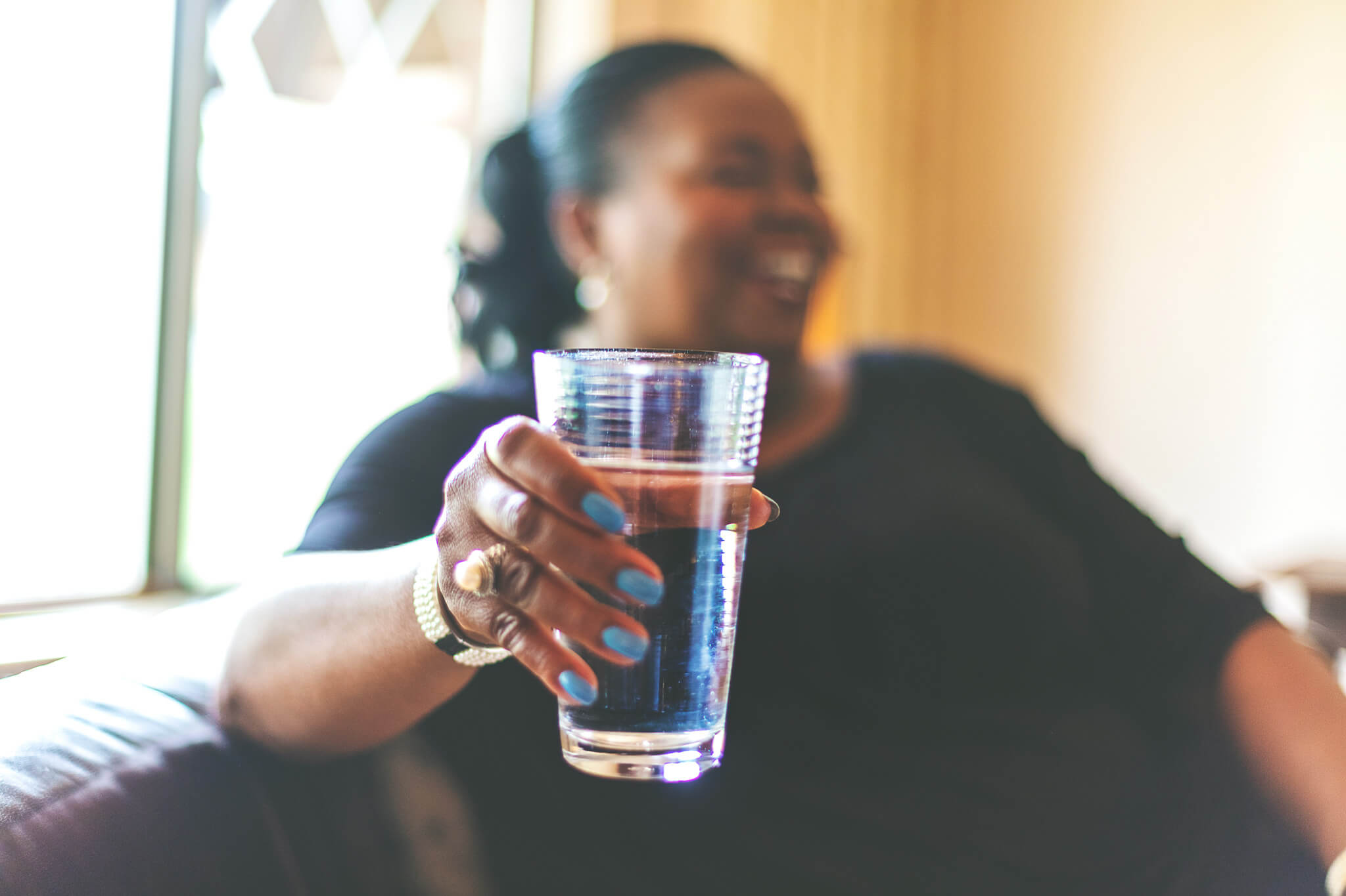 Adult African American woman smiling and holding a glass of water